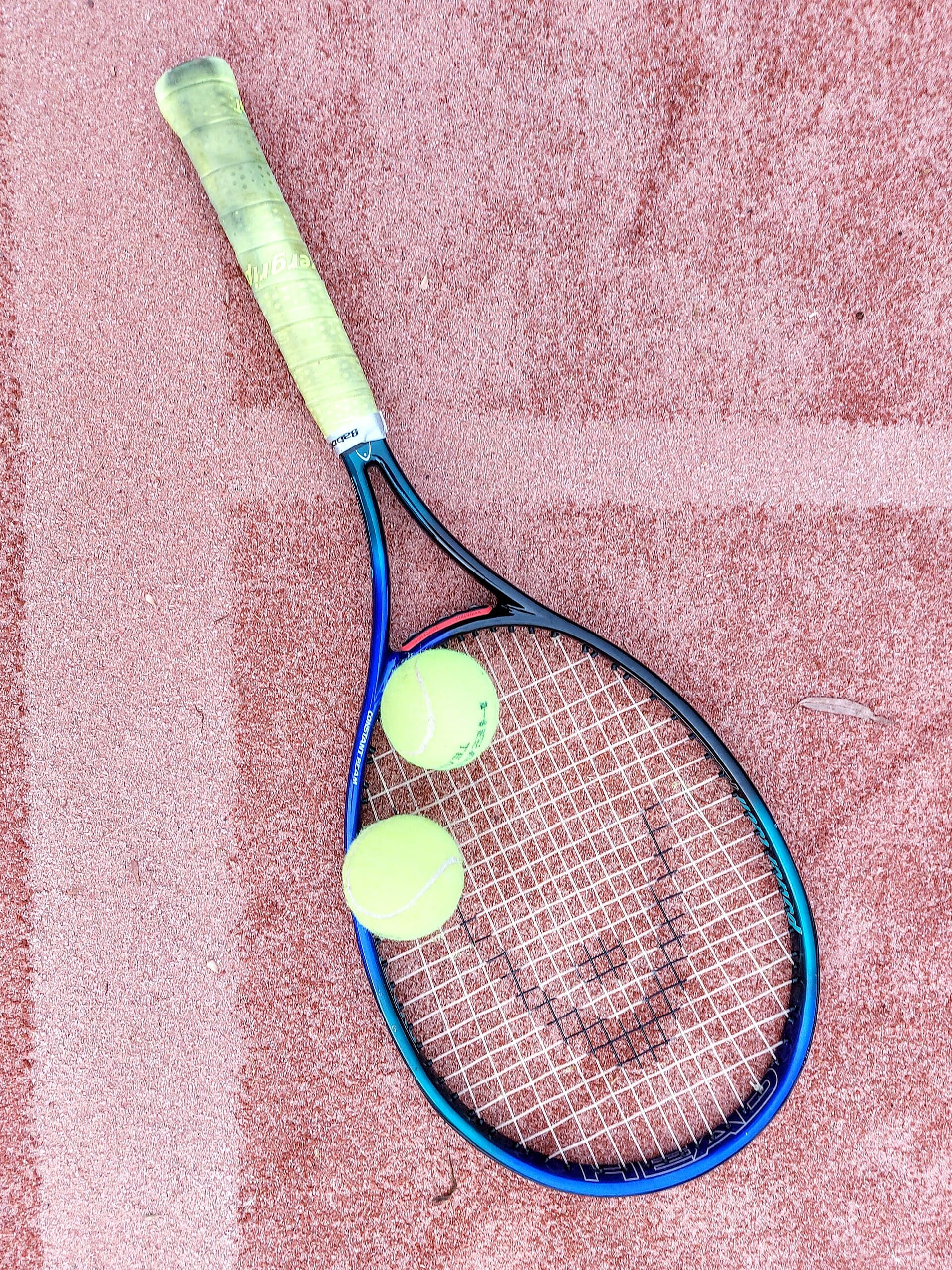 Tennis racquets and balls resting on a clay court
